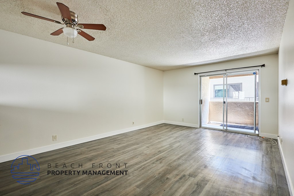 A room with a ceiling fan and a sliding glass door leading to a balcony.