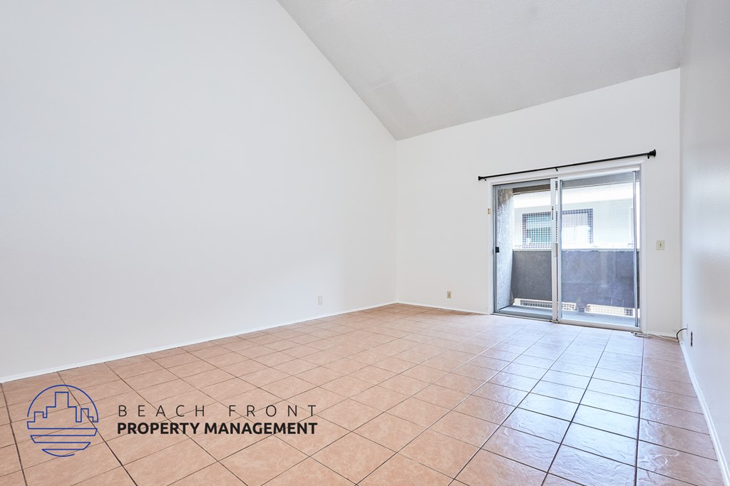 A room with a sliding glass door and tile flooring.