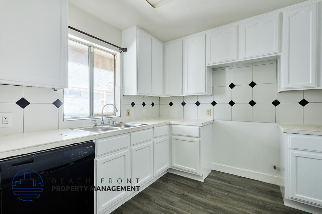 A kitchen with white cabinets and a black dishwasher.