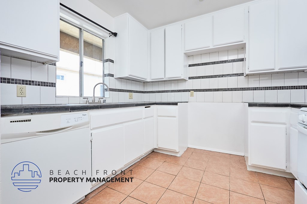 A kitchen with white cabinets and a tile floor.
