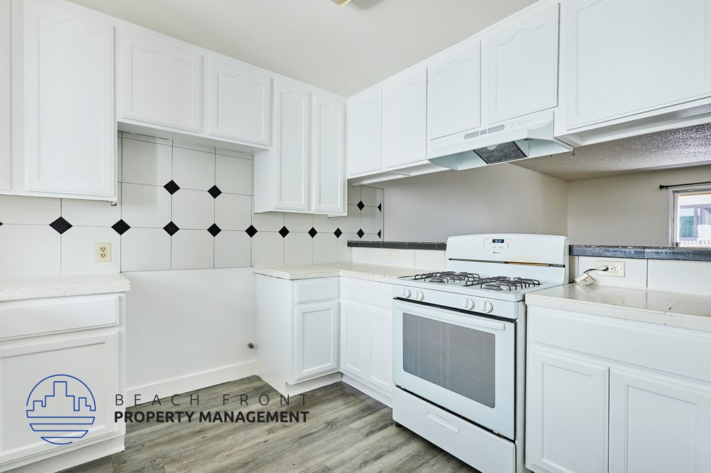 A kitchen with white cabinets and a stove top oven.