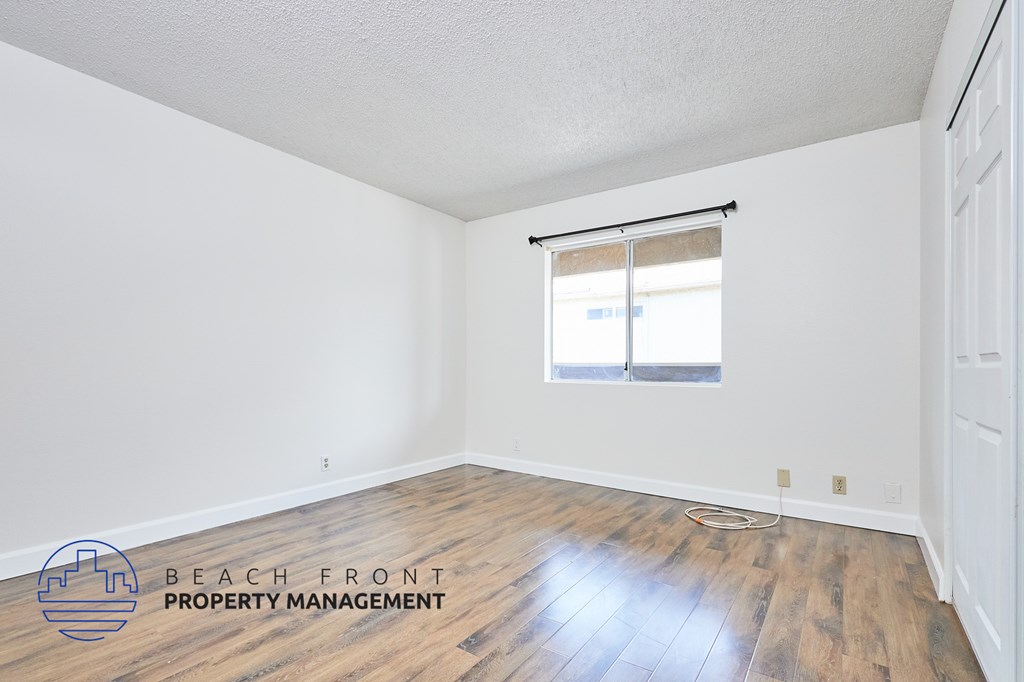 A room with wooden flooring and a window with blinds.