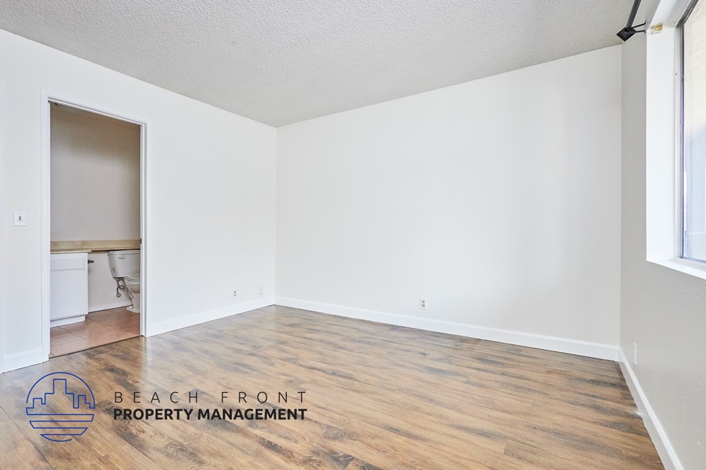 A room with wooden flooring and a logo for Beach Front Property Management.