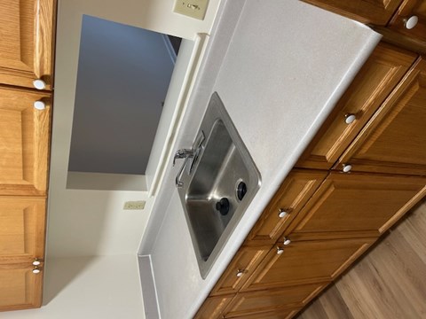 A kitchen with wooden cabinets and a stainless steel sink.