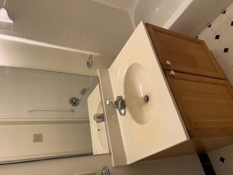 A white sink with a wooden cabinet above it.
