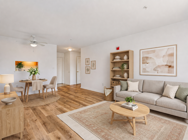 A living room with a couch, a coffee table, and a dining table with chairs.