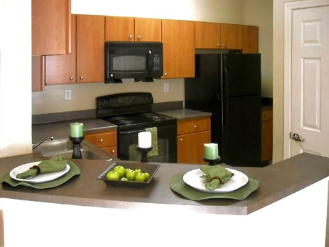 a kitchen with black appliances and a counter with plates of fruit