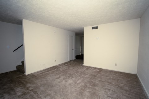 an empty living room with white walls and a carpet