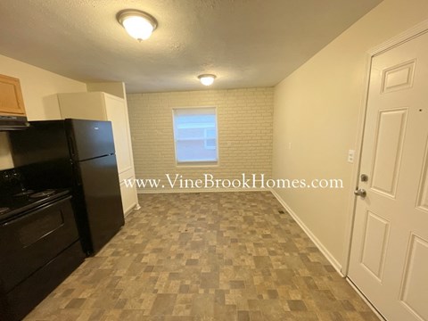 A kitchen area with a black refrigerator and a tiled floor.
