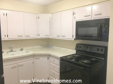 A kitchen with white cabinets and a black stove.