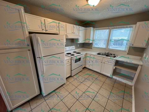 a remodeled kitchen with white cabinets and appliances and a refrigerator
