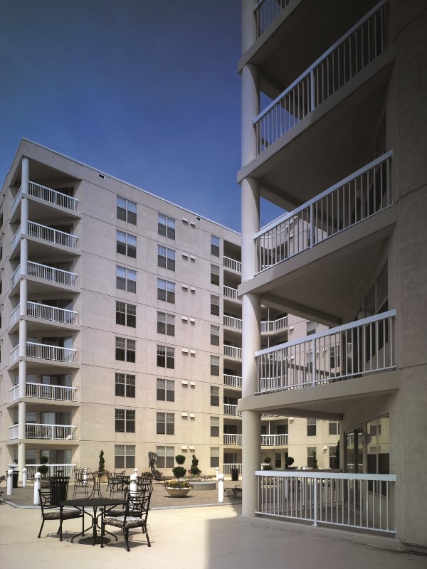 a large apartment building with tables and chairs in a courtyard