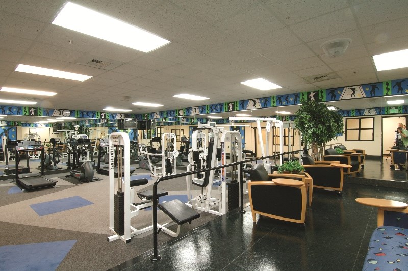 a gym with a lot of machines and chairs in it