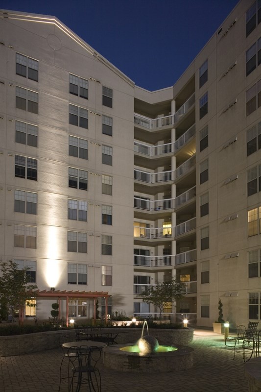 an apartment building at night with a fountain in the courtyard