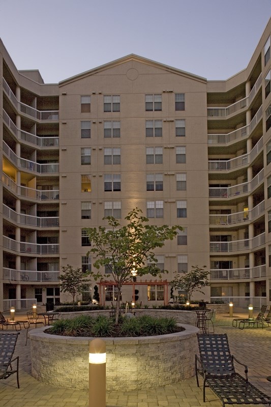 an apartment building with a courtyard with a tree and chairs