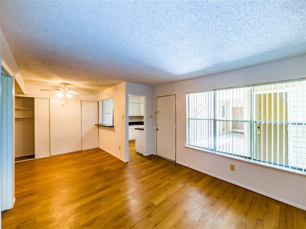 an empty living room with a hard wood floor and a window