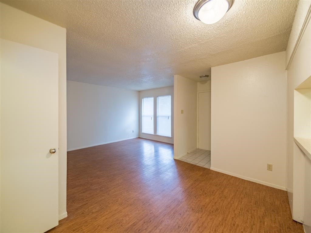 an empty living room and dining room with wood floors and white walls