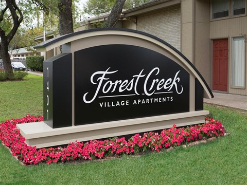 a sign in front of a building that says forest creek village apartments