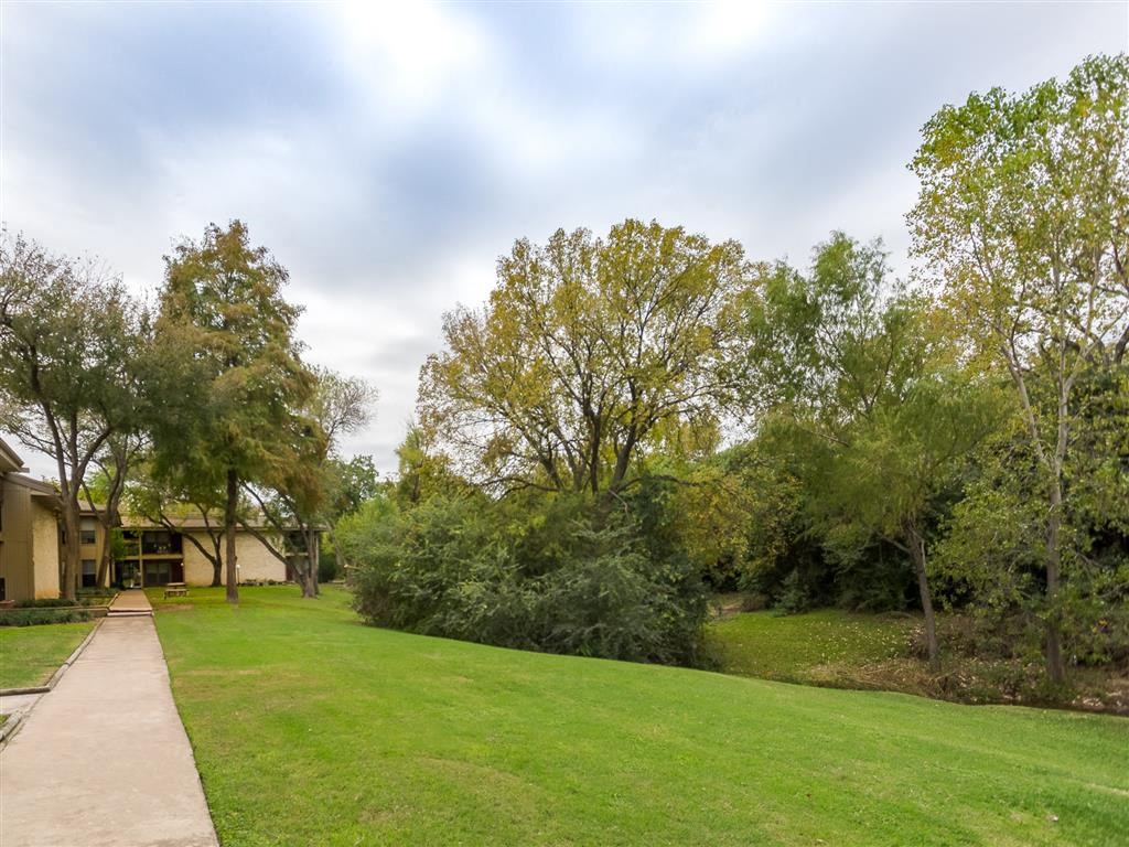 the yard of a house with a green lawn and trees