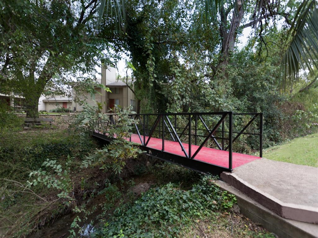 a bridge over a stream with a house in the background