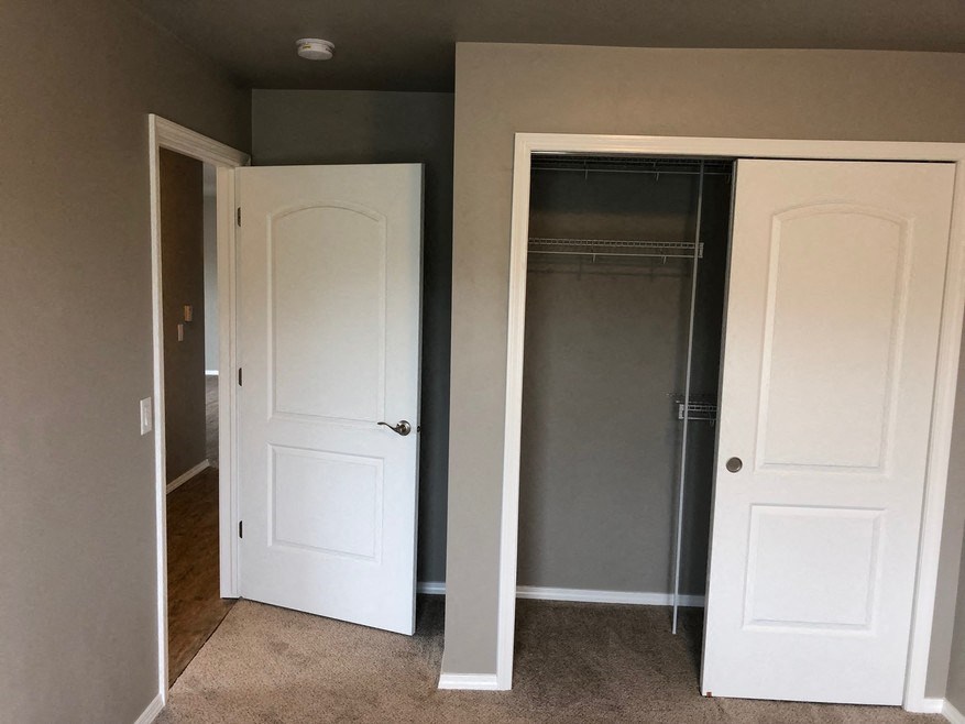 an empty closet with two doors and a closet mirrored door
