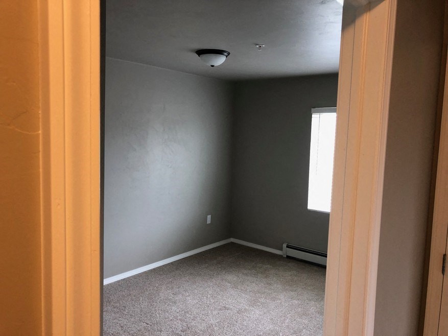 an empty room with a grey wall and a window