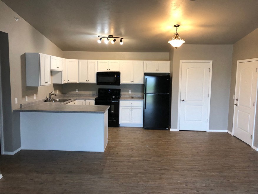 an empty kitchen with white cabinets and a black refrigerator
