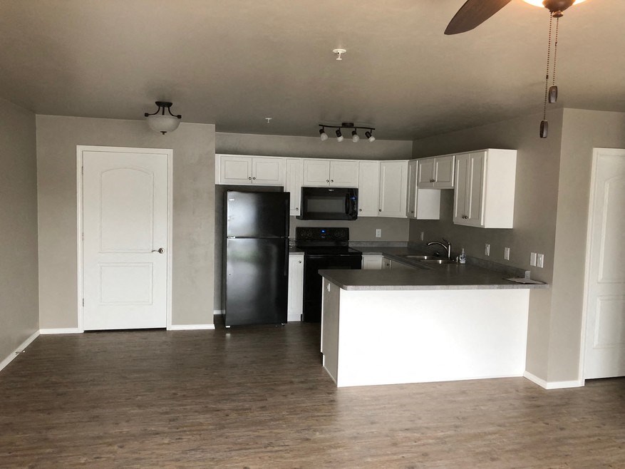 an empty kitchen with white cabinets and a black refrigerator