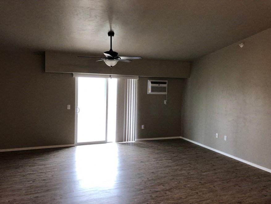 an empty living room with a ceiling fan