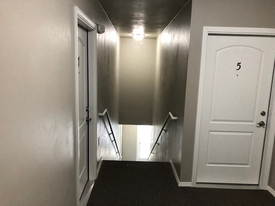 a hallway with white walls and stairs and a white door
