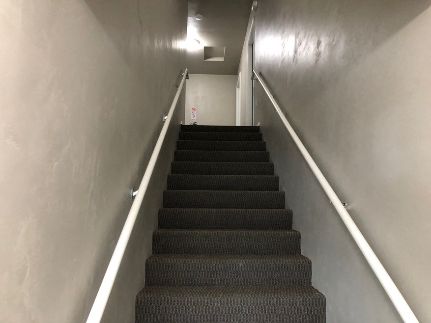 a flight of stairs with a metal railing and a white wall
