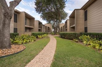 a walkway between two apartment buildings with trees in the background