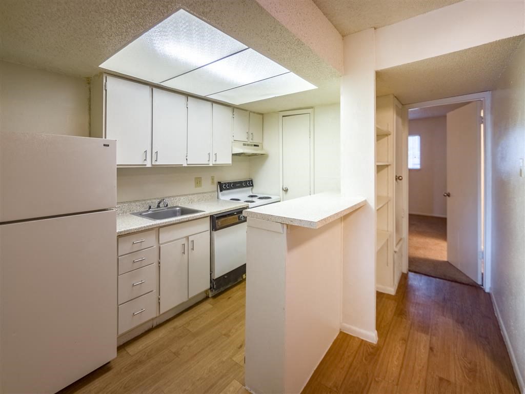 an empty kitchen with white cabinets and a refrigerator
