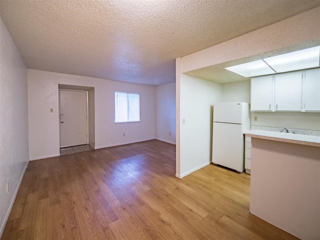 an empty living room and kitchen with a refrigerator and