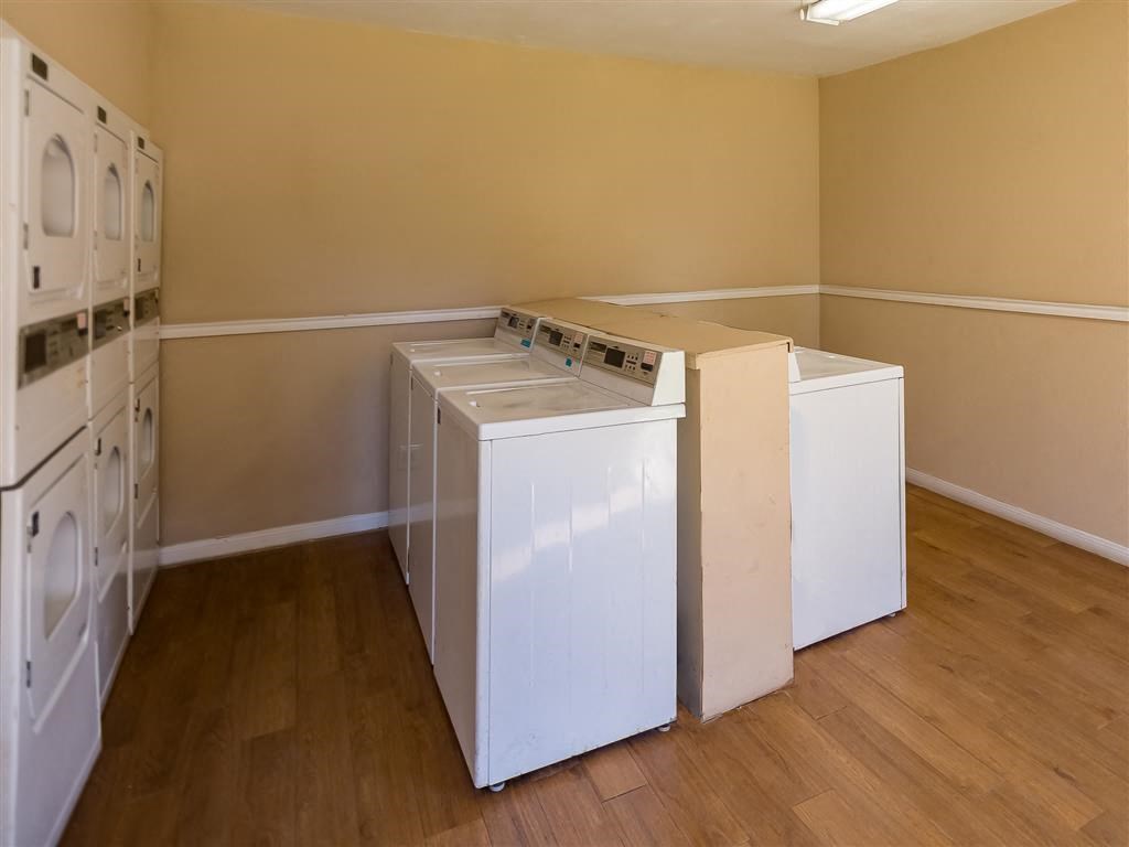 an empty laundry room with three washes and a dryer