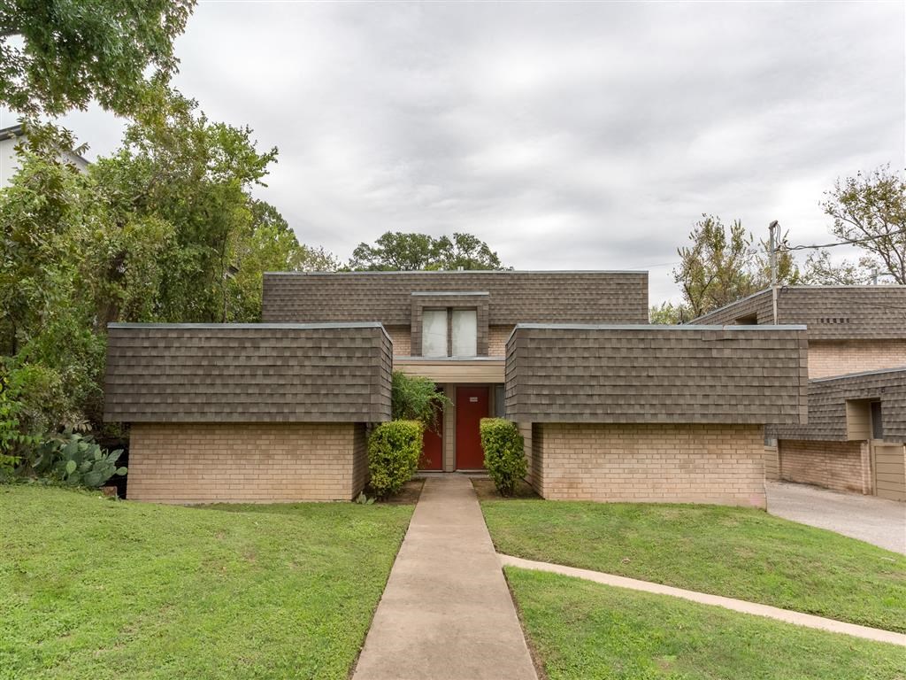 the front of a brick house with a red door