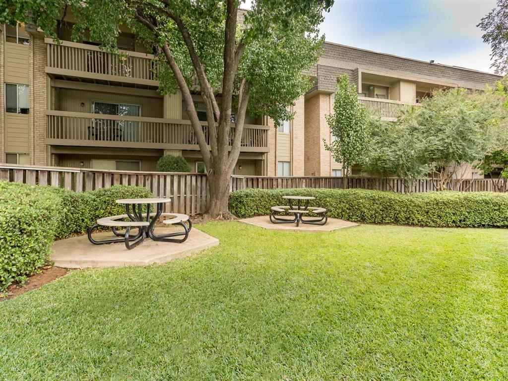 an apartment building with picnic tables in a grass yard
