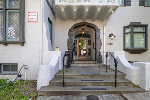 A white building with a black door and a sign that says "No Parking".