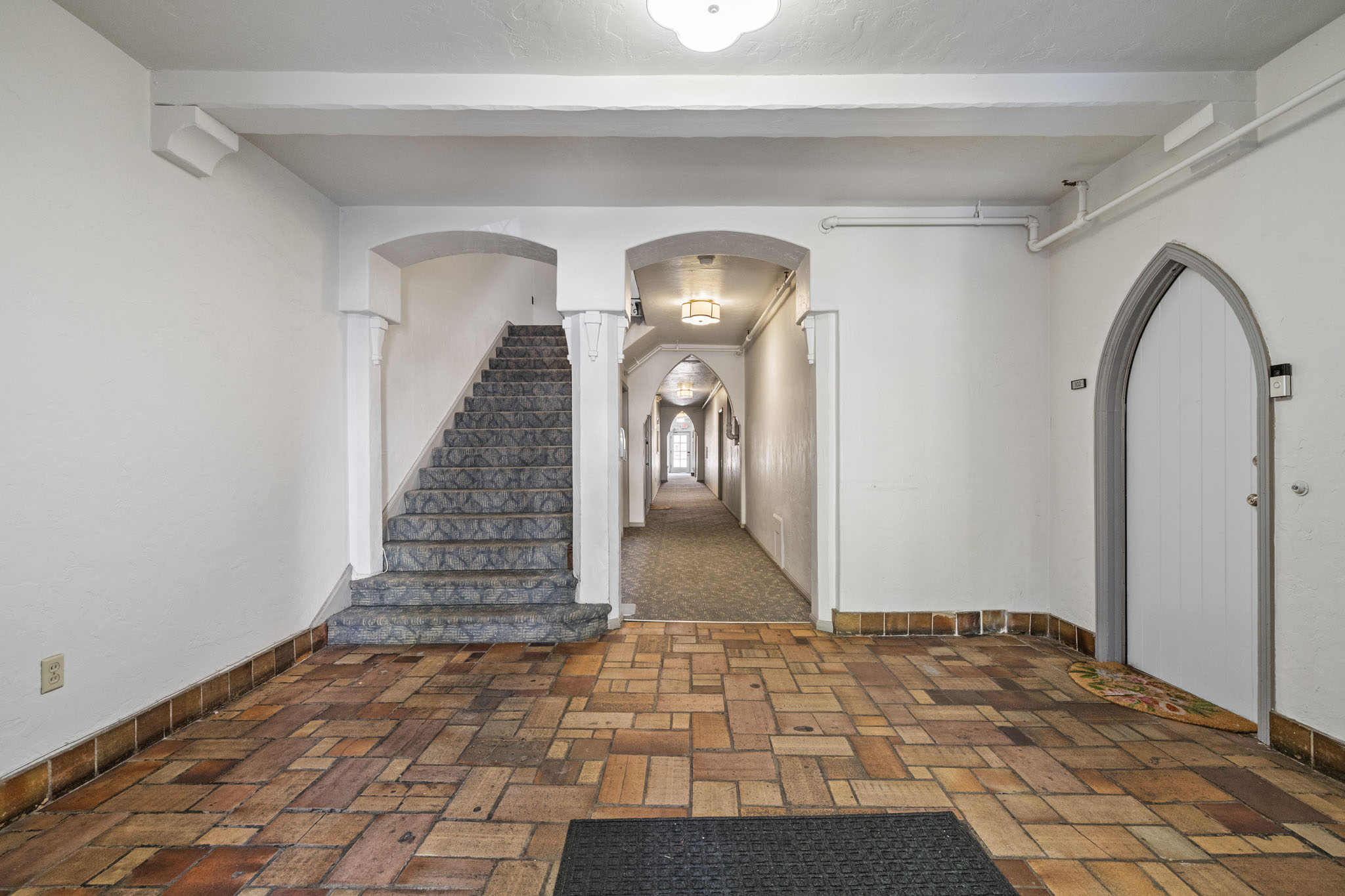 A hallway with a staircase and arched doorways.