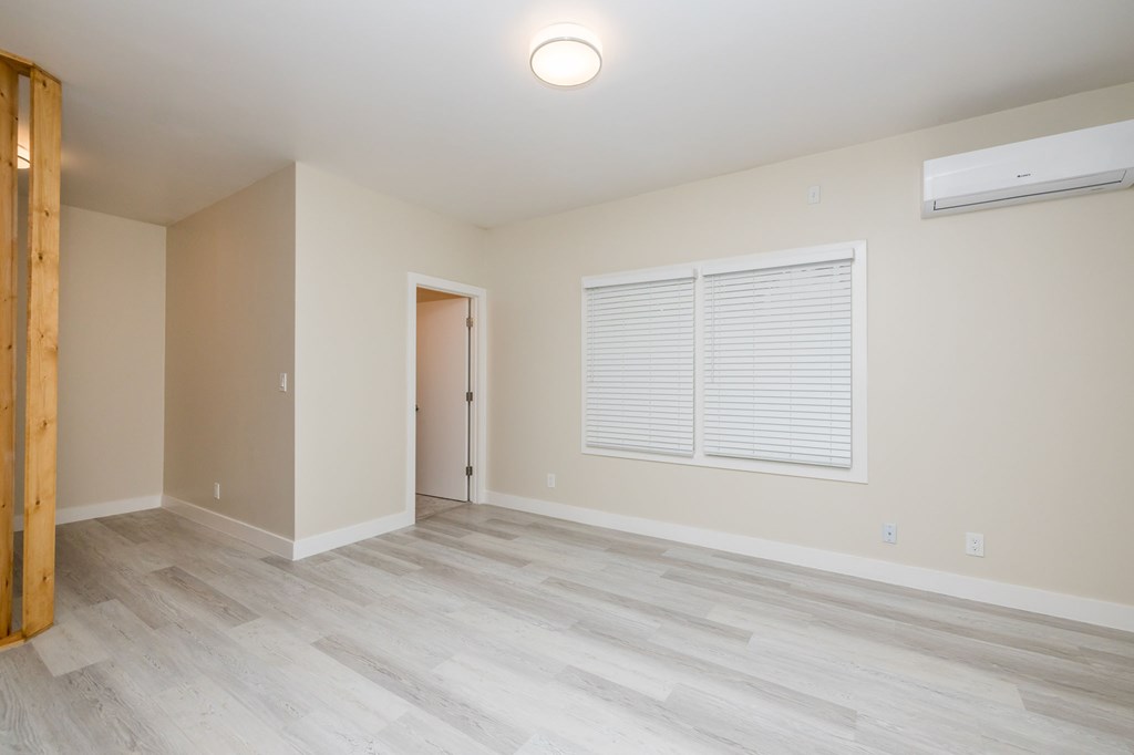 the living room of an empty home with a large window and wooden floors