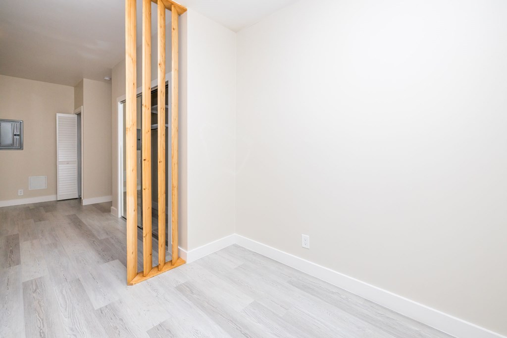 a room with white walls and wood flooring and a wooden doorway