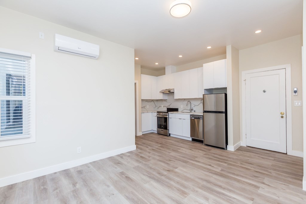 a renovated living room and kitchen with white cabinets and stainless steel appliances