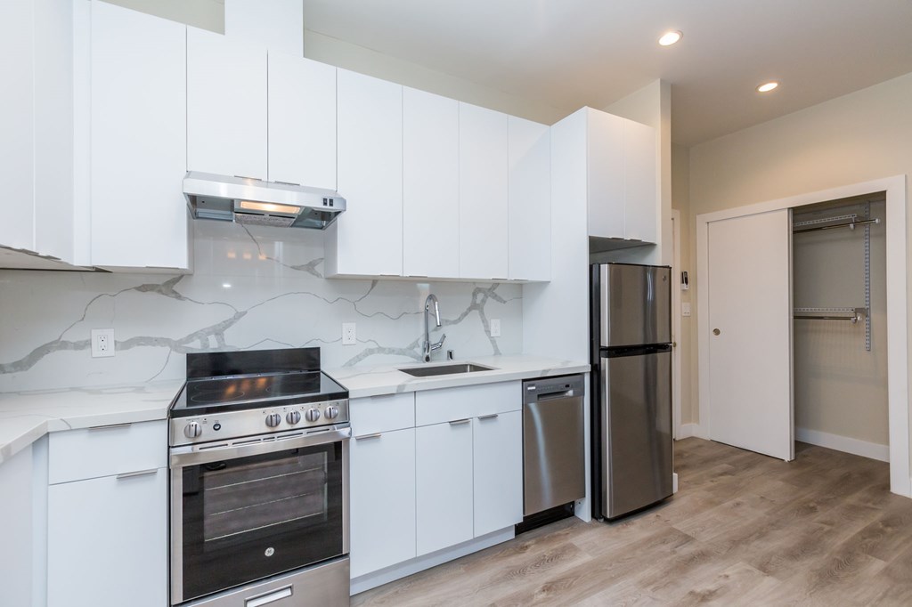 a white kitchen with stainless steel appliances and white cabinets
