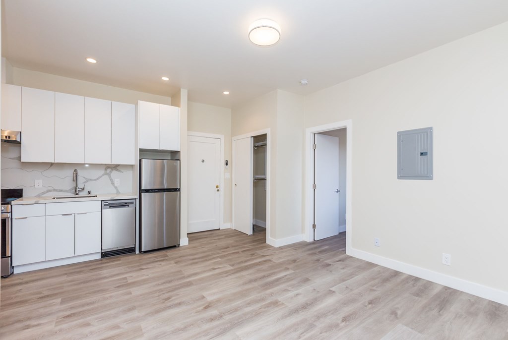 a renovated kitchen with white cabinets and a stainless steel refrigerator