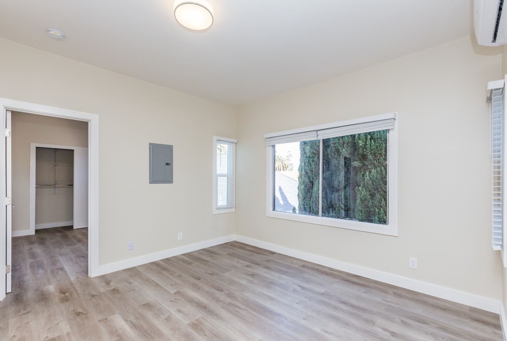 an empty living room with a large window and wooden floors