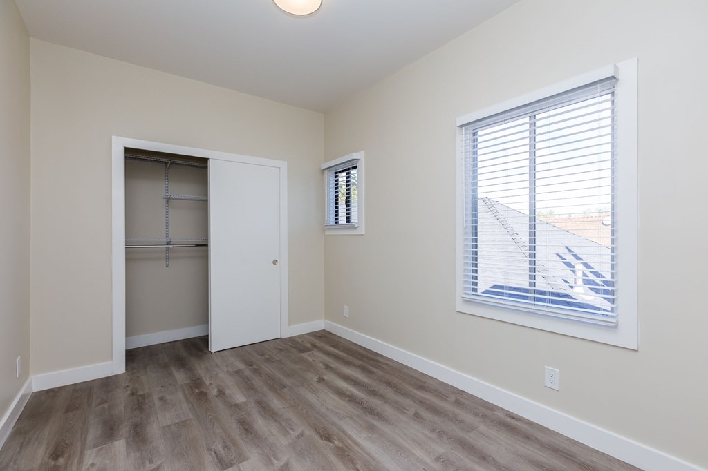 an empty bedroom with a closet and a large window