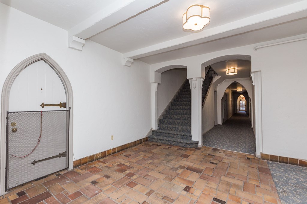 a hallway with arches and a tile floor and a staircase