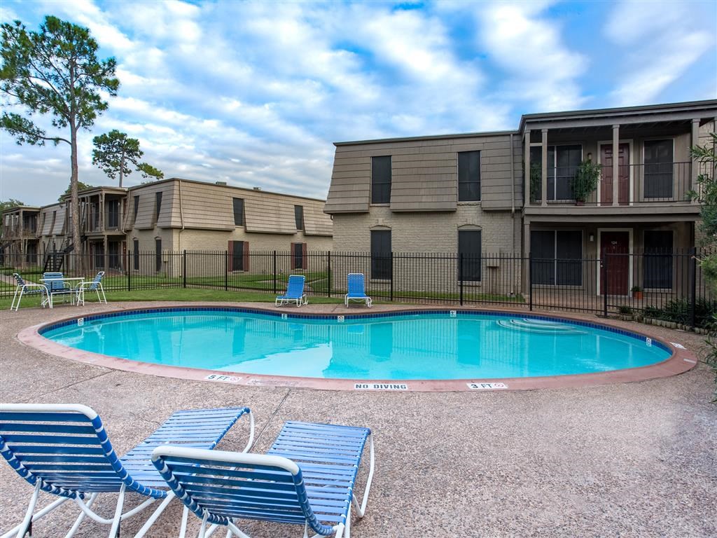 a resort style pool with blue chairs and apartments in the background