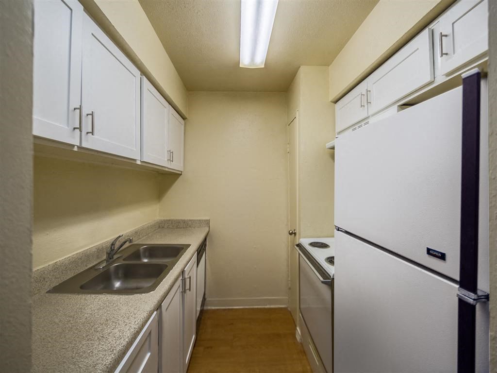 a kitchen with white cabinets and a sink and a refrigerator