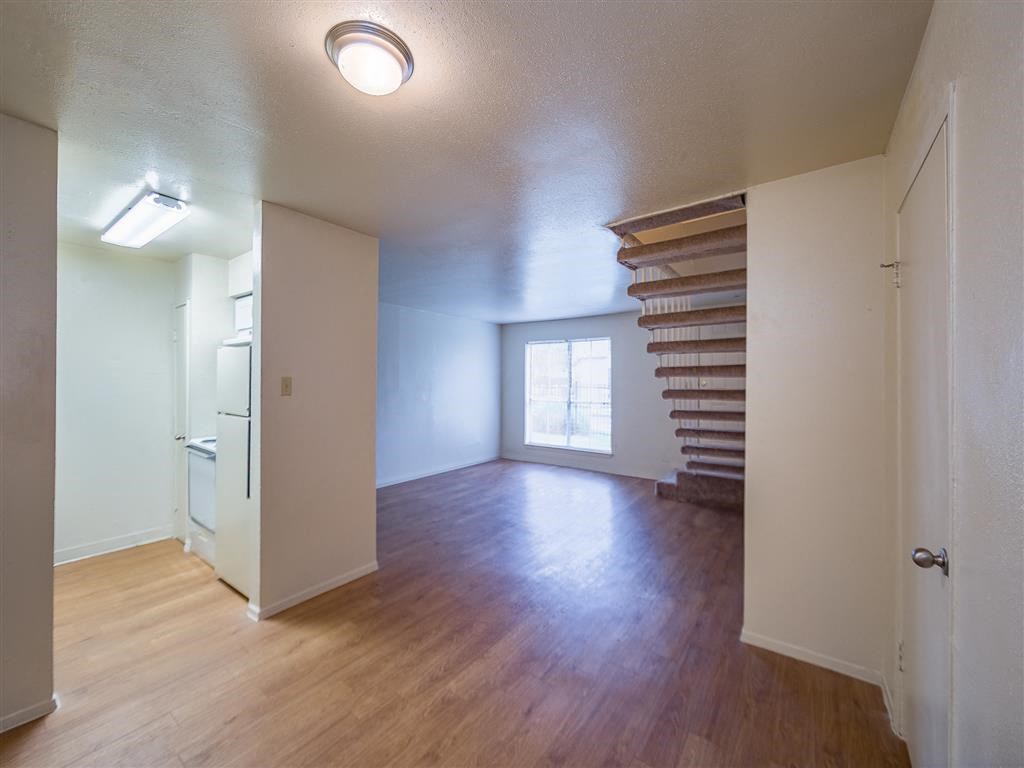 an empty living room with a wood floor and a staircase